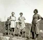 Systrarna Andersson iförda städrockar och en okänd gosse står utanför Livered 1:15 