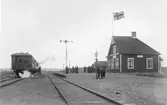 Grimetons järnvägsstation, som uppfördes vid Varberg-Ätrans järnväg år 1911. Ett tåg står och ångar på ena spåret och på stationsplanen finns en skara människor.