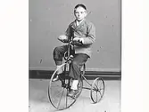 Pojkporträtt. Wilhelm Ranch sitter på en trehjulig cykel.