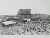 Fiskebod och flera båtar på en stenig halländsk strand.