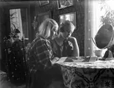 Två flickor vid ett bord. Flickan närmst kameran är Anna Karin Zackrisson. Anna Karin var dotter till fotografen Nannys syster Amy. Bilden är troligtvis tagen i fotografens bostad på Kyrkogatan.