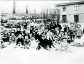 Bosgårdens barnträdgård på Lekskolegatan våren 1944. Barnen på bilden är mellan fyra och sex år gamla. De var där fyra timmar om dagen inklusive vilostunder. Under vilostunderna bjöds de på knäckebrödssmörgås med sirap. Bosgården drevs av stiftelsen ”Barnens Vänner”. Hunden hette Snuffsan.