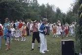Barn och vuxna dansar kring stången vid midsommarfirande på Ekensås cirka 1982. Sångare/ledare är Sven Olof 