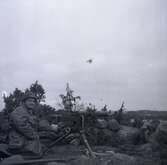 Militärövningen Ölandskriget. En soldat med kulspruta i lavett och en helikopter i luften.