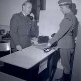 Bild från militärövningen Ölandskriget. En kommendat i telefon och en kvinna som håller i ett häfte.