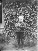 Pojke håller en kattunge i famnen, Harg, Uppland