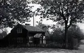 Bostadshus, okänd ort. Stuga med trädgård.