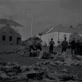 Torget på kvällen efter marknaden i Mörbylånga. Skräp på marken och folk som dricker. Skandinaviska banken - Åbrinks i bakgrunden.