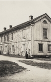 En kvinna står vid husknuten på den s.k. Boismanska gården, Växjö, ca 1920.