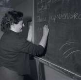 Bild tagen i samband med att flyktingar ifrån Ungern anlände 1956. Kvinna som skriver på en tavla i Godtemplargården. Hösten 56 - våren 57.