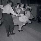 Bild tagen i samband med att flyktingar ifrån Ungern kom 1956. Män och kvinnor som dansar. Kvinnorna dansar i traditionella folkträkter i Godtemplargården hösten 56 - våren 57.