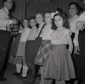 Bild tagen i samband med att flyktingar ifrån Ungern kom 1956.  En grupp barn och en man med dragspel och en kvinna i bakgrunden förmodligen i Godtemplargården i Borgholm.