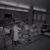 Två män i vita rockar i en konsumbutik.