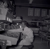 En man i vit rock som arbetar med varor på Konsum.