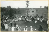 Västerås, Vallby friluftsmuseum.
Dans runt midsommarstången framför Tenngjutargården, Vallby friluftsmuseum. 1924.
