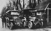 Två av de första taxibilarna i staden fotograferade vid droskstationen Allégatan x Yxhammarsgatan omkring år 1910.