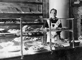 Fru Selma Broberg vid disken i sin bageributik vid Norrby Långgata omkring år 1915.