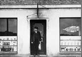 Handlanden F.R. Jägerström vid dörren till sin speceri- och matvaruaffär omkring år 1918.