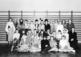 Maskerad i Norra skolan, utklädda elever och till höger, lärare Alfons Nilsson, till vänster övre raden, lärarparet Friskopp, sittande framför dem småskollärare Alice Eliasson.