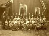 En samling personer utanför ett hus. Oidentiferat sammanhang år 1912.