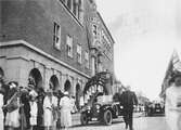 Kung Gustav V:s besök i Borås 1924. Ett ekipage med bilar och barn med flaggor står framför rådhuset.