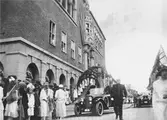 Kung Gustav V:s besök i Borås 1924. Ett ekipage med bilar och barn med flaggor står framför rådhuset.