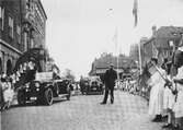 Kung Gustav V:s besök i Borås 1924. Ett ekipage med bilar och barn med flaggor står framför rådhuset.