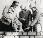 Grundstenen inmurad i Teleborgskyrkan, Växjö, februari 1974. 
Fr.v.: kontraktsprost Åke Rydeman, domprost Bengt Hallgren och en okänd murare.