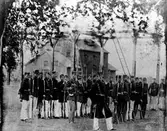 Bilden visar soldater uppställda på 2 led med gevär i hand. Med på bilden är bland annat August Bruno och Johan Sandberg från Alingsås.