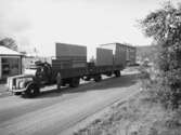 Transport på lastbil. Abrahamssons möbelfabrik AB Taberg. En man står utanför lastbilen och på sidan av lastbilen står texten, Rolf Fransson Huskvarna . Längre bort ser man företaget Ströms Verkstads AB i Taberg.