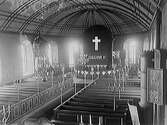 Interiörbild av Träslövs kyrka vid Oscar II:s död (8 december 1907), vilket framgår av altarets tillfälliga drapering. Notera kaminen till höger.
