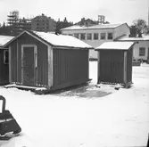 Mindre bodar uppställda på Trandögatan. I bakgrunden syns bygget av höghusen som karaktäriserar Druvefors.