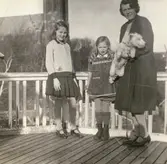 Laila Björck på Villa Björckås uteveranda tillsammans med döttrarna Ulla och Bibbi samt hunden som var en terrier och som hette Tuj eller Muff. Laila var hustru till doktor Erik Björck. Fotografi taget i mars 1930.

Numera har huset adressen Frölundagatan 25 B i Åby, Mölndal.