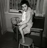 Ilse Tobiasson (född 1960, gift Glimberg), iklädd morgonrock, sitter på köksbordet hemma i familjens lägenhet på Krokslättsgatan 3 i Mölndal år 1964/65.