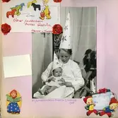 Luciafirande hos Rothwalls i Kållered 1955. Storebror Svante Ekman, iklädd stjärngossekläder, sitter med lillebror Manne i sitt knä. Text skriven i rött av deras mor Mary: 