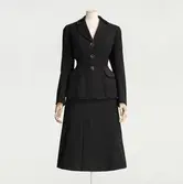 Ylledräkt i figurnära snitt, bestlld med två kjolar för variationsmöjligheternas skull och för att kjolen nöttes snabbare. Beställd från NK:s Franska damskrädderi av Margit Graffman (1900-1991) chef för NK:s konfektionsavdelning 1931 till 1953. Levererad juni 1948.