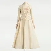 Klänning monterad på docka. Aftonklänning av siden med silverglittrande pärl- och paljettbroderier. Beställd från NK:s Franska damskrädderi av Eva Hökerberg född Bergström (1899-1990), chefredaktör på Idun 1928-1962. Hon bar klänningen på sin femtioårsfest 1949.