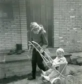 Kusin Ingela är på besök hos sin lille kusin Manne Ekman (född 1955) som sitter i en sulky utanför Villa Maribo (Streteredsvägen 29) våren 1957.