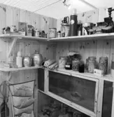 Utställning Tiotusen år. Utställningsdelen skafferiet, på hyllorna står termosar och kaffeburkar, olika produkter som skurmedel, fönstertvål, läderfärg Diamant Kenorator.