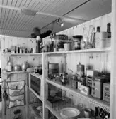 Utställning Tiotusen år. Utställningsdelen skafferiet med hyllor fyllda av det som ingick i ett skafferi för i tiden. På översta hyllan står ljusstakar, vaser,kaffekvarn med mera.