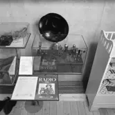 Utställning Tiotusen år. Utställningsdelen Radio, glasmontrar med olika radiodelar. Högtalare och radio tillhört fabrikant A.E Bolling Gränna.