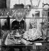 Utställning Tiotusen år. Utställningsdelen tågvagnarna, glasmonter 3:2 prydnadsblommor under glaskupa, gåva av Lilly Gustavsson, Huskvarna. Skål tillverkad av  Rörstrand, dockskåpsmöblemang, Spjälband ur Vivi Wallgrens donation 1962.