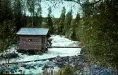 En liten stuga vid en fors.