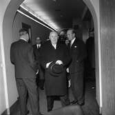 Christian Diors besök på NK, Nordiska kompaniet i Stockholm februari 1957. Personer, bland andra Kurt Jacobsson, står i korridor.