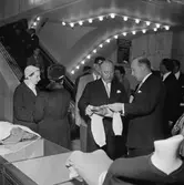Christian Diors besök på NK, Nordiska kompaniet i Stockholm februari 1957. Kurt Jacobsson visar en stickad tröja.