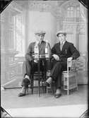 Ateljéporträtt - två unga män sitter vid ett bord med flaskor på, Östhammar, Uppland 1929