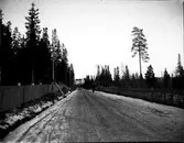 En väg som är omgiven av staket. Vägen går mot dövskolan.