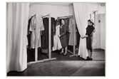 Beklädnadsateljéerna på NK (Nordiska Kompaniet). En kvinna hanterar plagg som hänger på klädställning. Vid sidan står en annan kvinna och håller ett draperi.