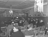 Sammanträde, antagligen kommunfullmäktige. Enar Berglund är ordförande. Efter väggen kan E.A. Edlund skönjas. Salen användes även av skolan. 