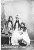 Ateljéfoto. Tre unga kvinnor flickor på en soffa, där den i mitten är klädd till Lussebrud.
(Eventuellt är fotot taget av Mathilda Ranch.)